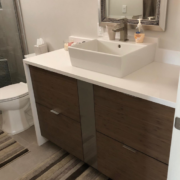 Modern bathroom vanity with wooden drawers and white vessel sink.